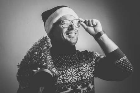 young man in Christmas clothes with a small Christmas tree, black and white photoの写真素材