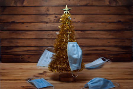 Pandemic and Christmas, Christmas tree with medical masks on a wooden backgroundの写真素材