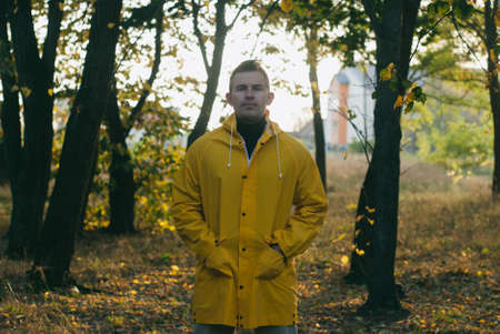 a man in a yellow raincoat in an autumn Park,の写真素材