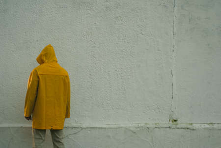 a suspicious hooded man is standing with his back to the wall,の写真素材