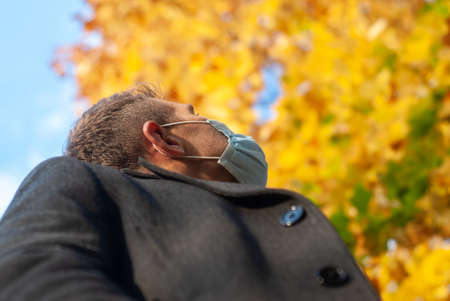 A man in a medical mask in an autumn Park, close-up,の写真素材