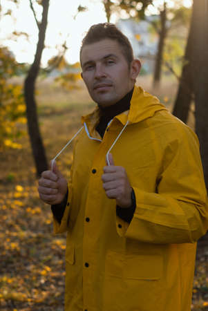 confident man in yellow raincoat in autumn Park,の写真素材