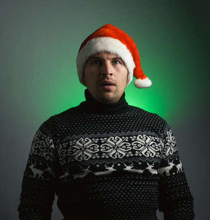 surprised man in a Christmas sweater and Santa hatの写真素材