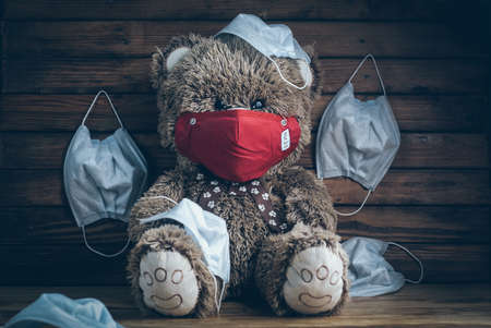 Teddy bear in red medical mask on woodenの写真素材