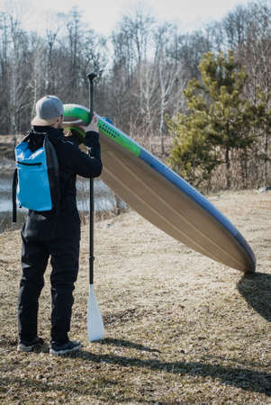 paddle board traveler, a man in a dry wetsuit stands with a paddleの写真素材