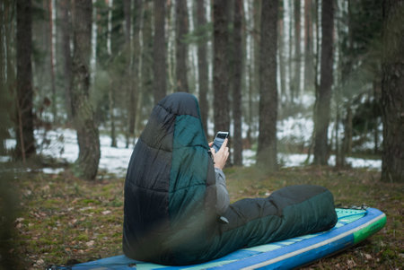 a man in a sleeping bag in the woodsの写真素材