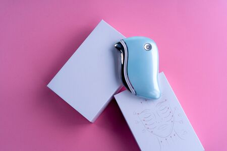 guasha device ultrasonic massage pink on a blue background is a bright color for a cosmetologistの写真素材