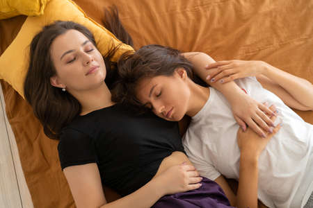 lesbian couple in love sleeping in bed togetherの写真素材