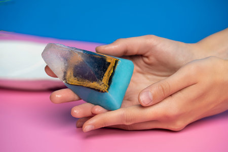 beautiful soap in the form of a crystal girl holds in her hands on a pink backgroundの写真素材