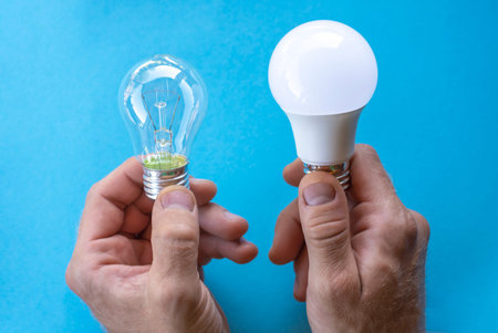 An incandescent lamp and an energy-saving lamp in hands on a blue background. energy saving concept