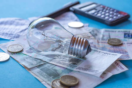 ncandescent lamp, Russian money and a calculator on a blue background. The concept of energy saving, payment for electricityの写真素材