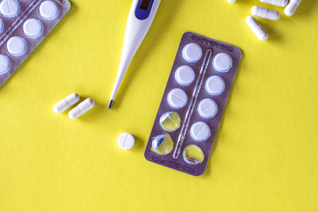 Pills and a thermometer close-up on a yellow background. medicine and healthcare.