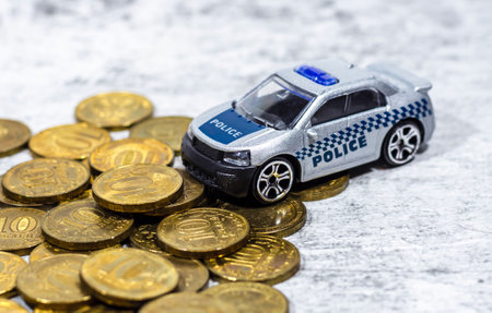 A toy car with the inscription "POLICE" stands on gold coins. The concept of paying taxes, finesの写真素材