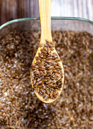Flax seeds on a wooden spoon against the background of seedsの写真素材
