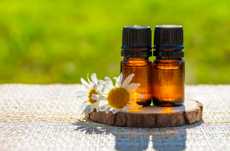 Chamomile essential oil. Dark glass bottle with essential oil and chamomile flowers on the tableの写真素材
