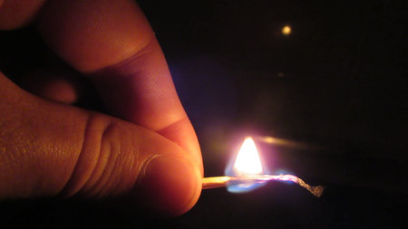 Close up of a man's hand lighting a single match in the dark
