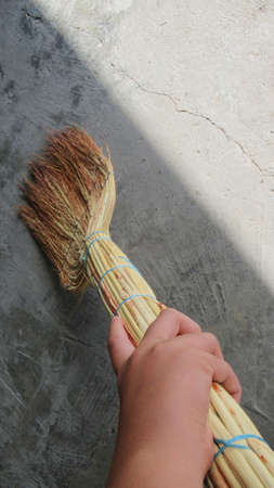 Male hand holding a sweep for cleaning his backyardの写真素材