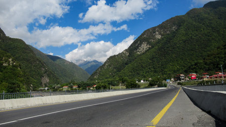 Beautiful view of a big green Caucasian mountain forests and blue bright sky with white clouds