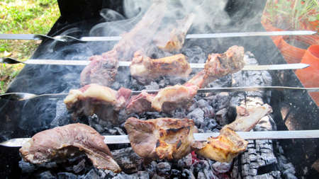 A close up of a raw meat peaces on a wire metal for barbecueの写真素材