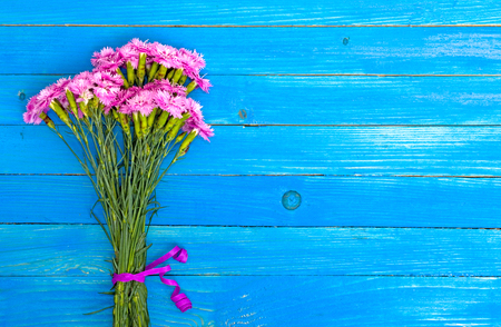 Small bouquet of red carnations on the blue shabby boards.の写真素材