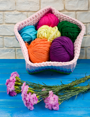 Knitted handmade basket and blue carnations on the shabby boards.の写真素材