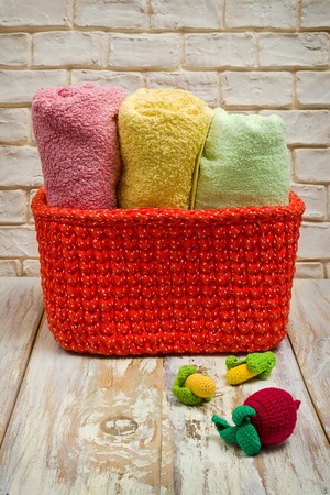 Handmade knitted basket and towels on white worn boards.の写真素材