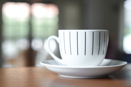 Cup of coffee on a wooden desk and living room backgroundの写真素材