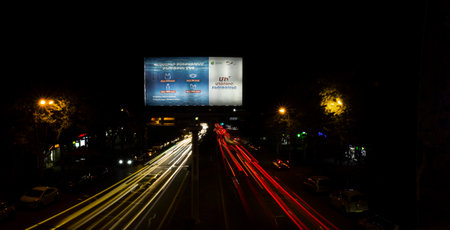 Yerevan, Armenia - October 27, 2022: Light trails from cars passing by a street advertising banner, which calls not to pollute the environment with plastic, long exposureのeditorial素材