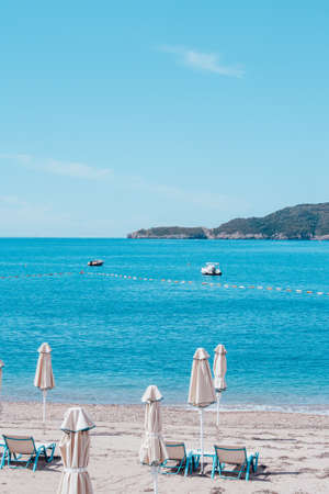 Sandy beach with sun beds and umbrellas on sunny day. Sunny vacation concept on beach, Montenegro.の写真素材
