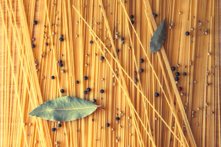 Artistic Spaghetti scattered on the table with bay leaf and black pepper peas. Italian food conceptの写真素材