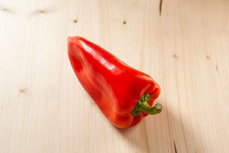Red bell pepper on a wooden background, top view. Fresh red pepper is organic vegetable, close-up. Vitamin red product, minimum calorie contentの写真素材