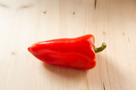 Red bell pepper on a wooden background, top view. Fresh red pepper on wooden table, space for your design or text. Organic concept of single vegetableの写真素材