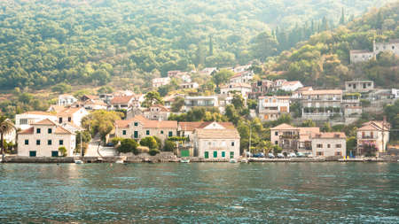 Beautiful Mediterranean seascape with houses tiled roofs on the background of mountains on a sunny day. Italian seascape concept. Traveling by shipの写真素材