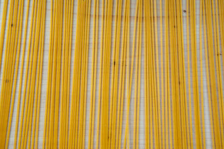 Dry spaghetti pasta grouped on cutting board background. Yellow uncooked pasta on wooden board background. Food background. High quality photoの写真素材