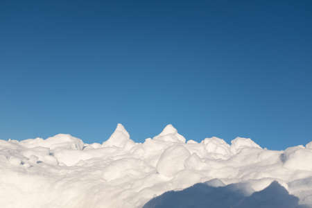 Fluffy snow lying on hill and blue sky around, after of heavy snowfall. Snowdrifts with blue sky for poster, calendar, post, screensaver, wallpaper, postcard, card, banner, cover, headerの写真素材