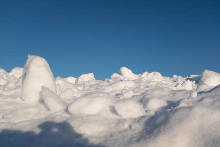 Fluffy snow lying on hill and blue sky around, after of heavy snowfall. Snowdrifts with blue sky for poster, calendar, post, screensaver, wallpaper, postcard, card, banner, cover, headerの写真素材
