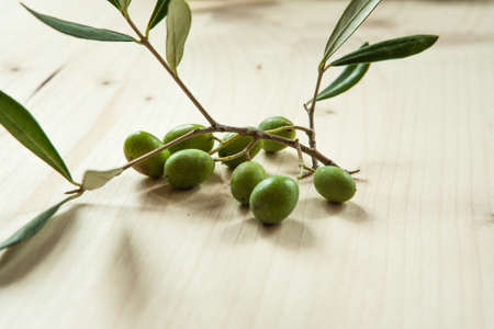 Branch with olives on wood table background, Concept and idea of food cook rustic still. Green olives with leaves for publication, poster, screensaver, wallpaper, postcard, banner, cover, postの写真素材