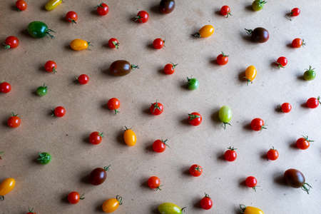 Red yellow brown cherry tomatoes are scattered on a gray background, upper view. Colorful cherry tomatoes for publication, poster, screensaver, wallpaper, postcard, banner, cover, post. Healthy dietの写真素材