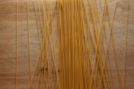Pasta spaghetti on a wooden board. Italian pasta. Yellow Spaghetti scattered on the table. Food backdrop, Italy. Spaghetti artistic background. High quality photoの写真素材