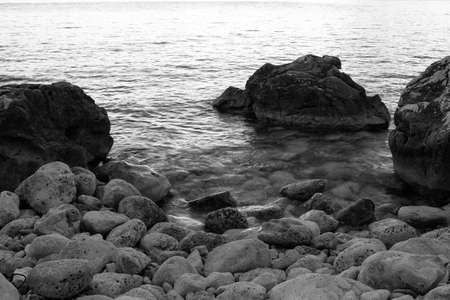Background of stone beach with rocks, close-up. Grey stone beach for poster, calendar, post, screensaver, wallpaper, postcard, card, banner, cover, website. Black and white high quality photoの写真素材