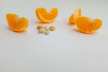 Still life with four wedges orange and five seeds on white background, close-up. Tangerine with seeds. Ripe citrus composition for publication, poster, calendar, wallpaper, banner, cover, websiteの写真素材