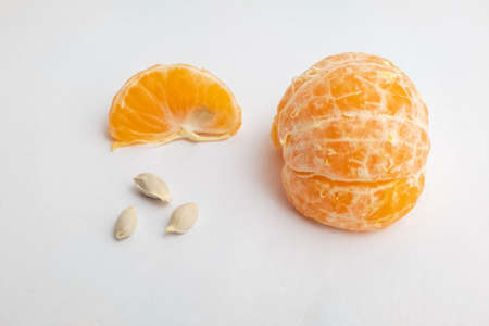 Still life with wedges tangerine and three seeds on white background, close-up. Orange with seeds for publication, poster, calendar, post, card, banner, cover, website, space for your design or textの写真素材