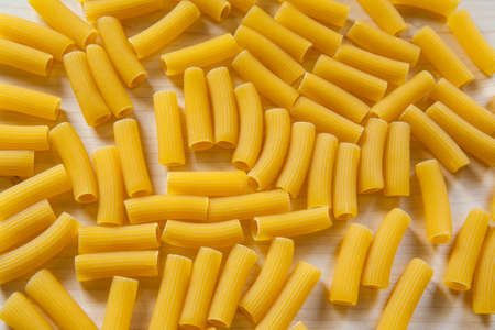 Top view raw macaroni as background, close up. Italian macaroni pasta on a white table for branding, calendar, postcard, wallpaper, poster, banner, cover, website. A place for your design or textの写真素材