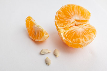 Still life with wedges tangerine and three seeds on white background, close-up. Orange with seeds for publication, poster, calendar, post, card, banner, cover, website, space for your design or textの写真素材