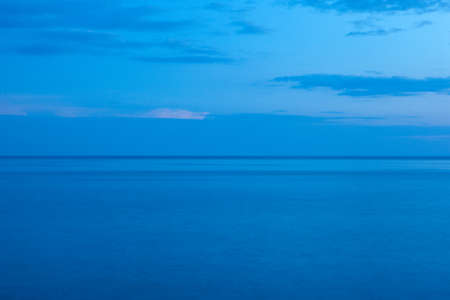 Background from the blue sea and the blue-blue sky with horizont line in the middle. Blue seascape for publication, poster, screensaver, wallpaper, postcard, banner, cover, post. High quality photoの写真素材