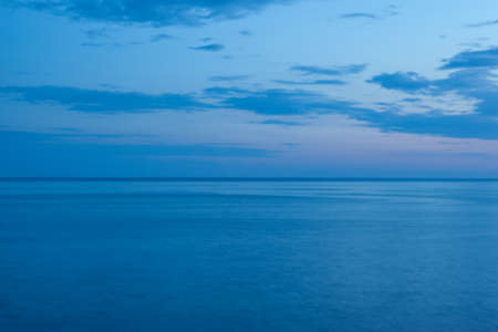 Background from the blue sea and the blue-blue sky with clouds and horizont line in the middle. Blue seascape for publication, poster, screensaver, wallpaper, postcard, cover, post. High quality photoの写真素材