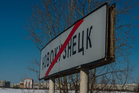 An old road sign denoting the completion of the city against the background of blurred city...