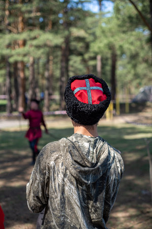 A boy in a red cap and a black t-shirt stands with his back against the background of a forest.の写真素材