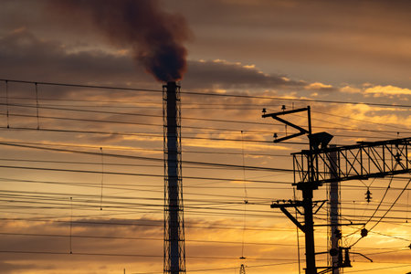 Industrial landscape with smoke from chimney and power lines at sunsetの写真素材