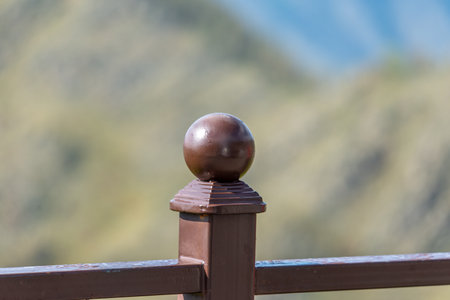 Close-up of a bronze ball on a fence in the mountainsの写真素材